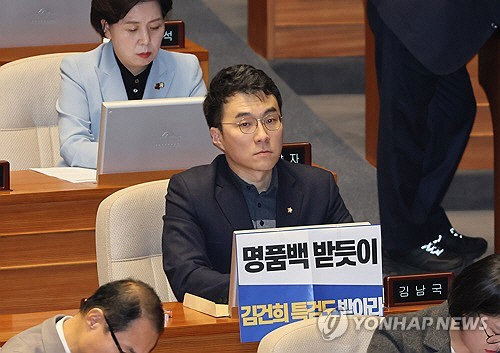 무소속 김남국 의원이 28일 오후 국회 본회의에서 김건희 여사 특검법 수용을 촉구하는 손팻말을 붙이고 있다. [연합뉴스]